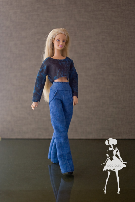 Фотография куклы барби в полный рост в коротком топе c длинными рукавами и джинсах с высокой талией