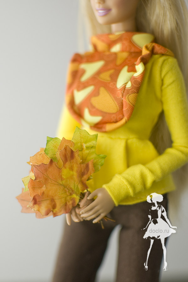 Увеличенная фотография кленовых листьев из бумаги в руках у куклы барби